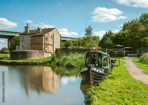 A converted canal narrowboat acts as a tearoom with a small outdoor garden seating area on the Leeds Liverpool Canal, near Wigan