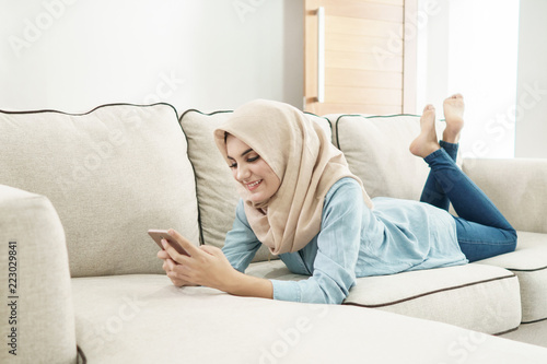 beautiful housewife wearing hijab texting on mobilephone while l