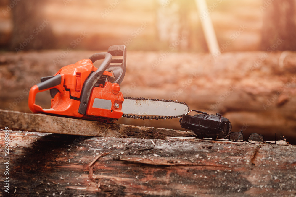 Close-up of chainsaw lies on sawn wood sawmill. Concept logging industry