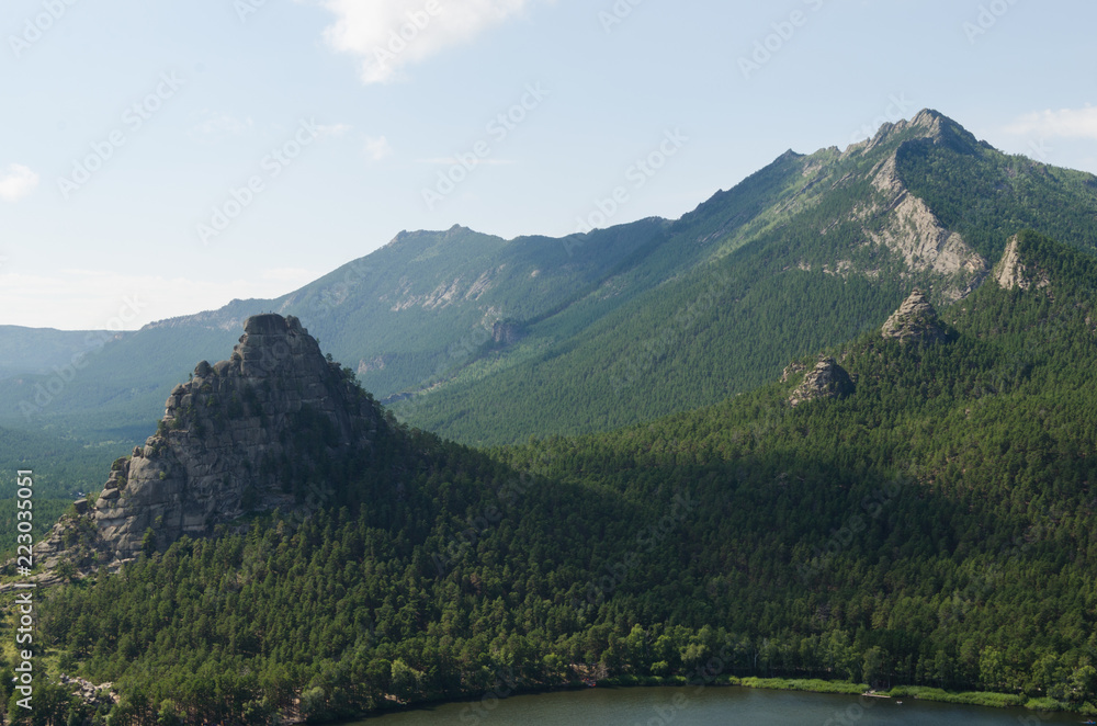 Landscape of mountains covered with green coniferous forest.
