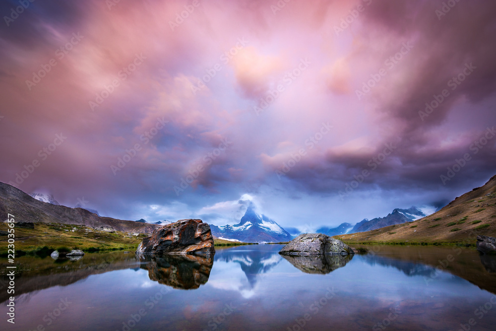 Beautiful sunrise with pink clouds at lake Stellisee with a view of the Matterhorn