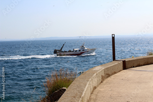 paysage de la côte ou front de mer Roses en Espagne avec chalutier © toutouchien02440