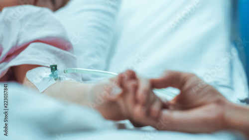 Recovering Little Girl Lying in the Hospital Bed Sleeping  Mother Holds Her Hand Comforting. Emotional Family Moment.