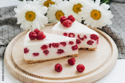 Two pieces of delicious cake with raspberries on wooden board