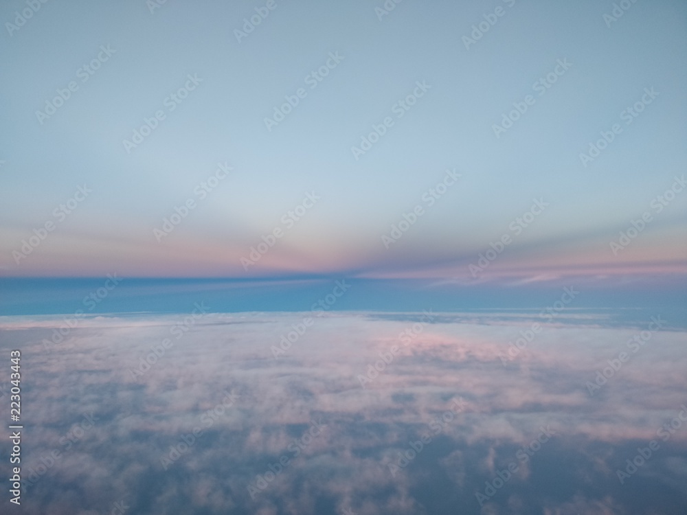 Cockpit view of the sunset light effects during cruise between a cloud layer.