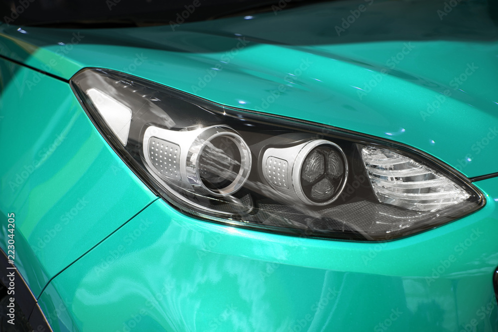 clean white headlight of a new blue luxury car from the saloon. close-up of the front right headlight