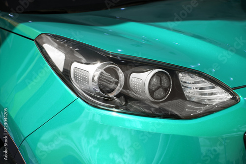 Obraz na płótnie clean white headlight of a new blue luxury car from the saloon. close-up of the front right headlight w salonie