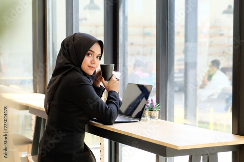 Islam woman working in cafe and drinking a coffee.
