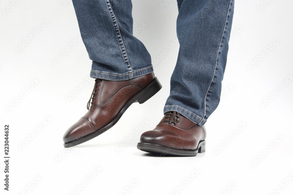Men's legs in jeans shod in classic brown Oxford shoes Photos | Adobe Stock