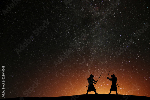 Silhouette of two samurais against the starry sky. Deadly warriors with swords © es0lex