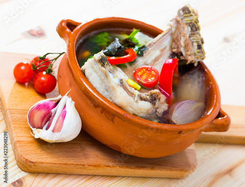 Soup of lamb with vegetables, lemon, onion and greens, served in bowl photo