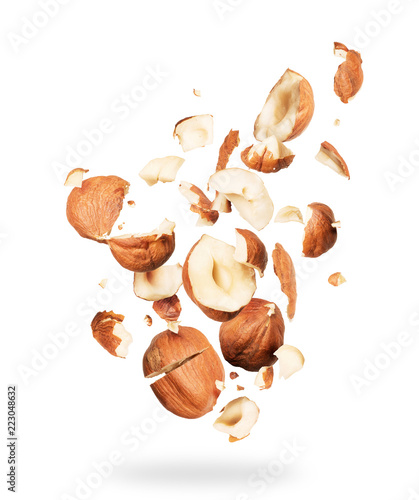 Hazelnuts crushed into pieces, frozen in the air on a white background photo