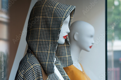 closeup of winter coat with hood on mannequin in fashion store showroom for women