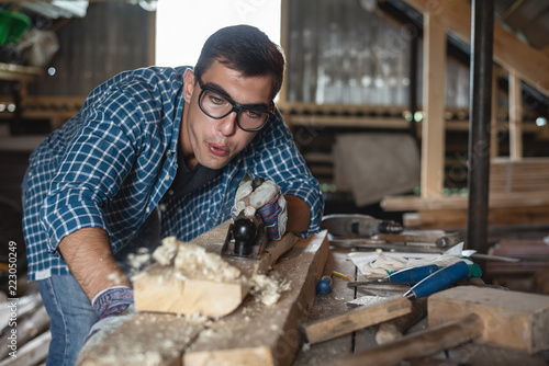Portrait of a man in goggles blows sawdust from the Board when woodworking planer