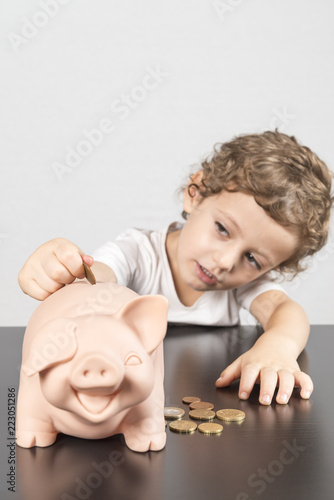 Child inserting coins in a piggy bank
