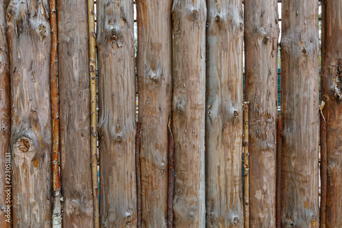 A fence made from brown round vertical pine logs. Natural log background