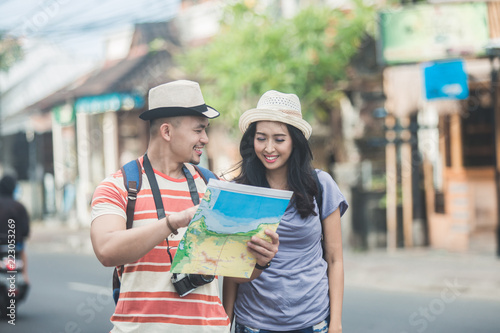 two young backpackers searching direction on location map while 