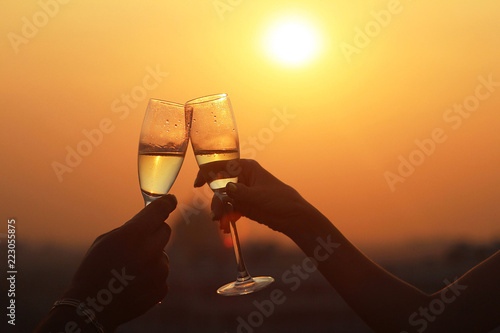 Two glasses of champagne or wine, couple dating concept, romantic celebration of engagement or anniversary on the sundown lights.