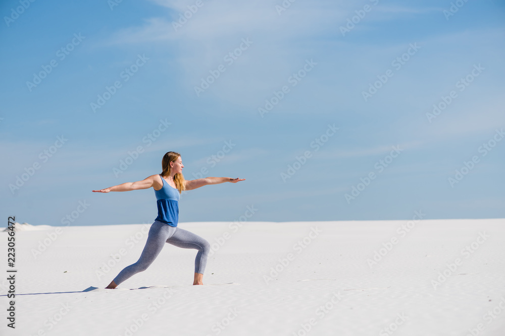 Sportive woman make warrior pose in desert Sportive woman make warrior pose in desert