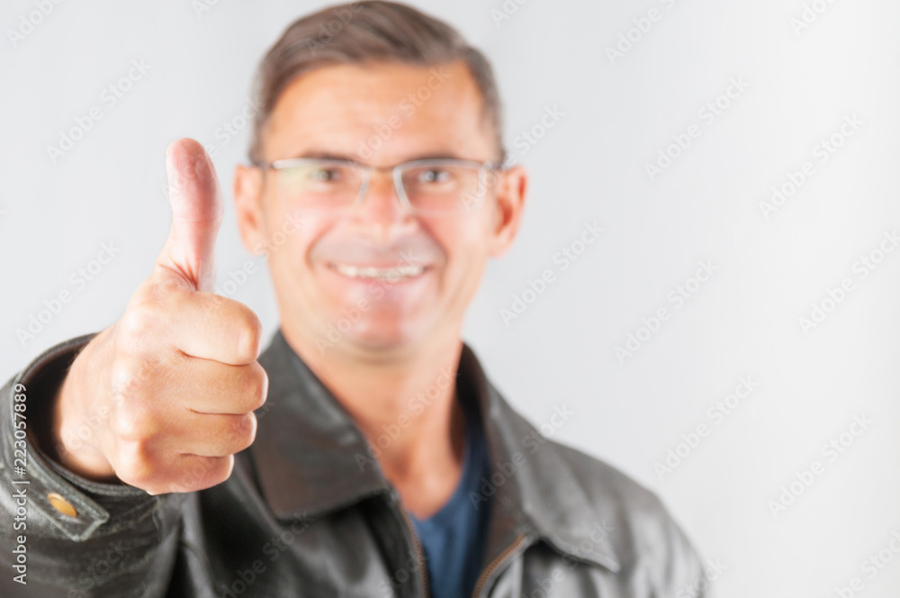 Smiling man in eyeglasses showing thumb up gesture on gray background Smiling man in eyeglasses showing thumb up gesture on gray background