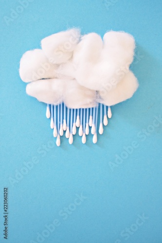 Cotton ball as a wool and earsticks as rain or snow on a blue background - concept for rain or fast with cotton swabs and cotton balls