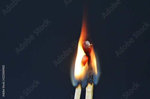 Two burning matches against a black background look like a couple cuddling and being intimate with each other - concept symbolizing fiery love