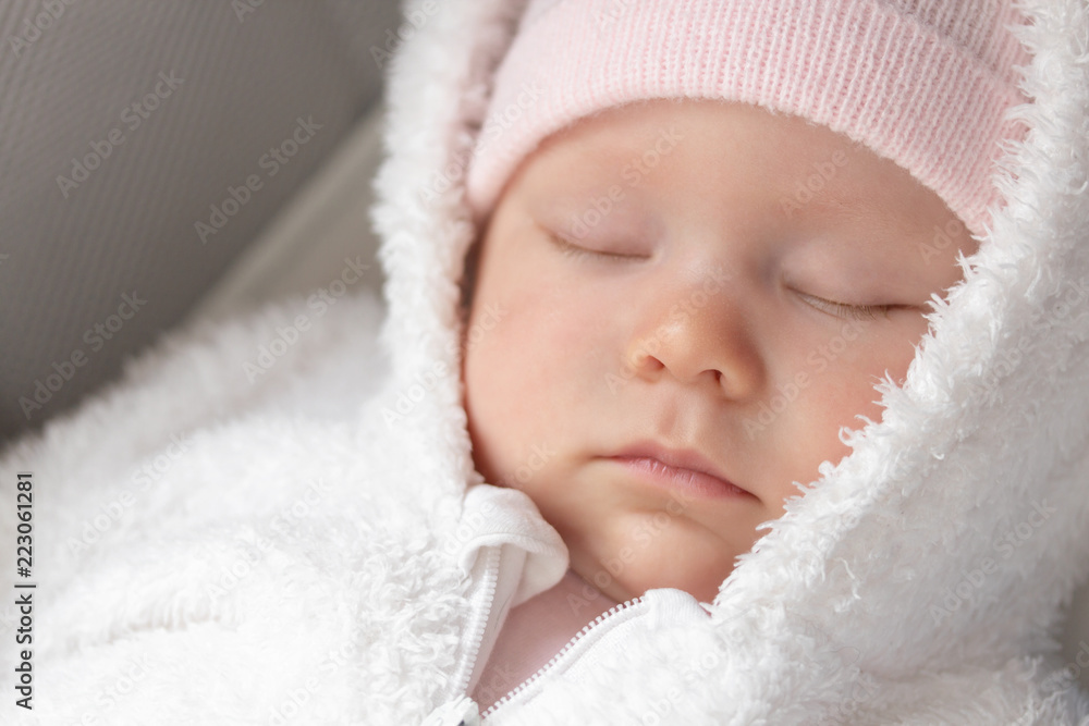portrait of a sleeping newborn dressed in a warm fur suit and hat. sleeping little baby girl close-up. portrait of a sleeping newborn dressed in a warm fur suit and hat. sleeping little baby girl close-up.