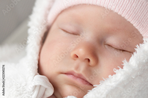 portrait of a sleeping newborn dressed in a warm fur suit and hat. sleeping little baby girl close-up.