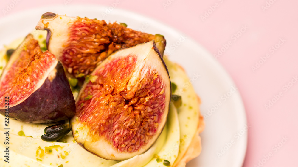 Delicious tart with fresh figs and pistachios on pink pastel backgrounds Delicious tart with fresh figs and pistachios on pink pastel backgrounds
