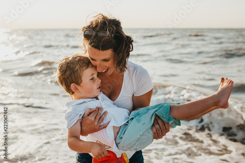 Pregnant Mother And Her Little Boy At The Beach At Sunset
