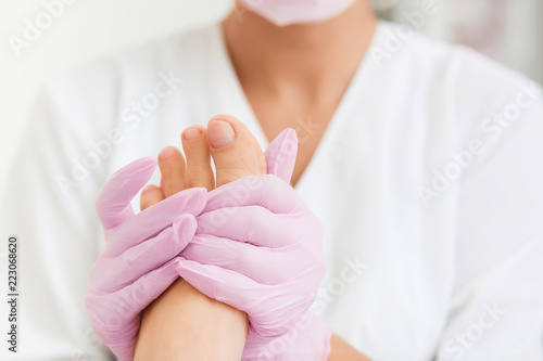 Professional foot massage using moisturizing foam.Final stage of professional pedicure.Skin softener, smoothing out hard skin.Patient visiting podiatrist. Foot treatment in SPA salon.Podiatry clinic. © YURII MASLAK