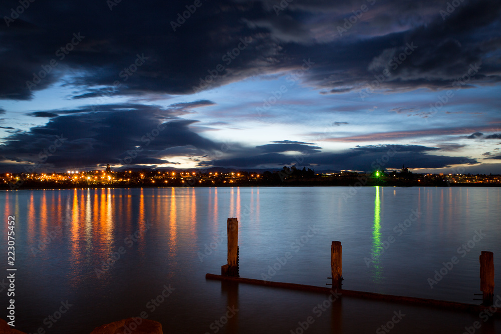 Reflections of the town lights in the bay in the evening on a still night at Caroline Bay, New Zealand