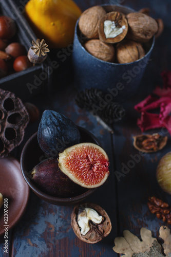 Fresh organic figs, nuts and autumn leaves on wooden board and dark stone table. Healthy lifestyle, seasonal fruit, sweet dessert, selective focus