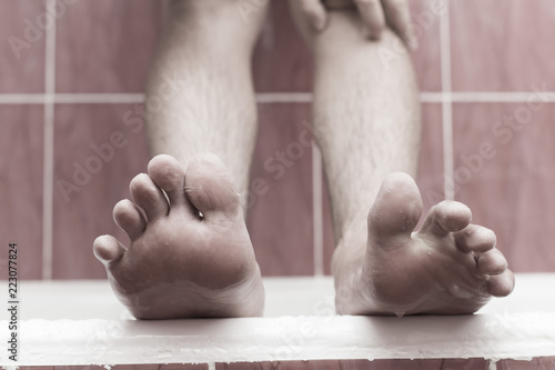 A man cleans his foot in the bathroom