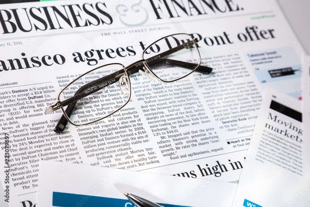 Glasses And Pen On Financial Reports And Newspaper Close-up Glasses And Pen On Financial Reports And Newspaper Close-up
