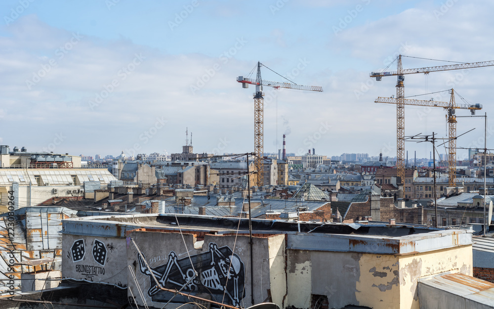 Saint Petersburg, Russia - April 2018: View of the city from the roof of old houses in historical downtown at sunny day, construction cranes, graffiti