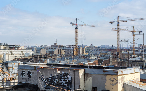 Saint Petersburg, Russia - April 2018: View of the city from the roof of old houses in historical downtown at sunny day, construction cranes, graffiti