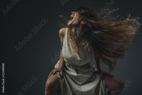 Crazy, deranged young woman screaming with frustration, expressing madness and rage photo