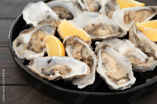 Fresh oysters with cut juicy lemon on plate  closeup