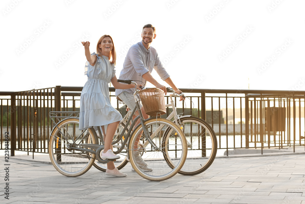 Happy couple riding bicycles outdoors on summer day