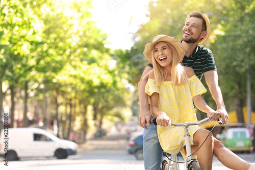 Happy couple riding bicycle together on street