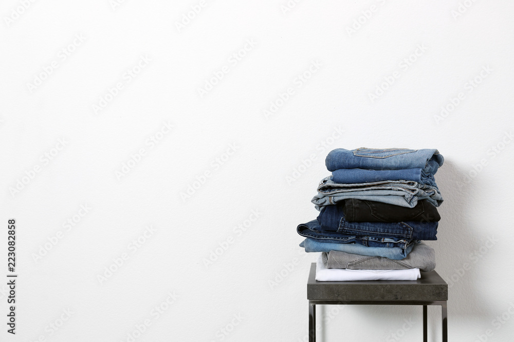 Stack of different jeans on table against white background. Space for text Stack of different jeans on table against white background. Space for text