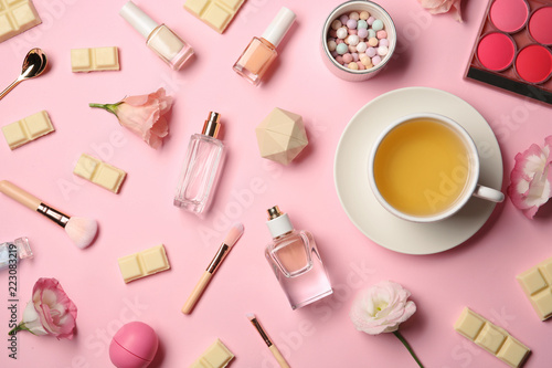 Flat lay composition with cup of tea, cosmetics and chocolate on color background