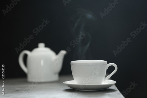 Cup of tea and saucer on table against dark background