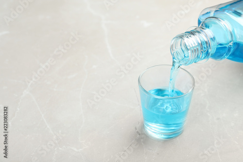 Fototapeta Naklejka Na Ścianę i Meble -  Pouring mouthwash in glass and space for text on light background. Teeth hygiene
