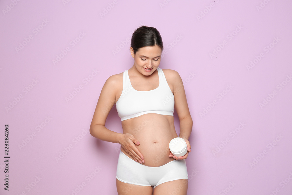 Pregnant woman holding body cream on color background Pregnant woman holding body cream on color background