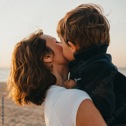 Pregnant Mother And Her Little Boy At The Beach At Sunset
