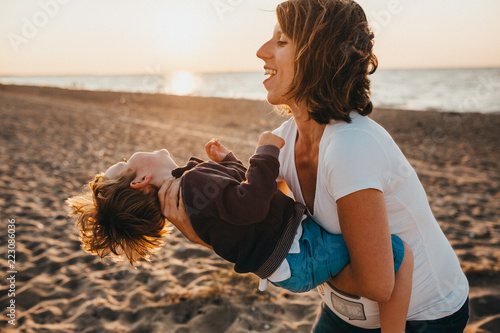 Pregnant Mother And Her Little Boy At The Beach At Sunset