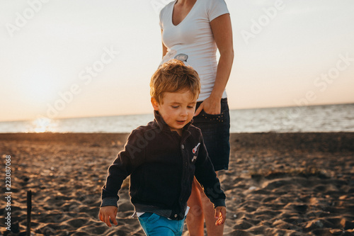 Pregnant Mother And Her Little Boy At The Beach At Sunset