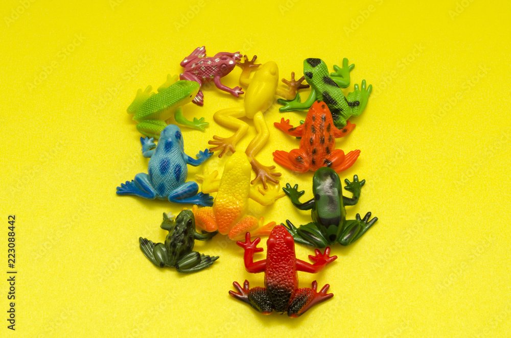 Plastic toy frogs on yellow background. Toy frogs on yellow background